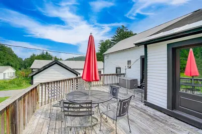 a patio with a table and chairs and red umbrellas at Hawley Home with Deck and Mtn Views Swim, Ski and More! in Hawley