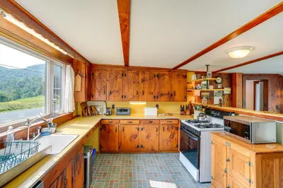 a kitchen with wooden cabinets and a large window at Hawley Home with Deck and Mtn Views Swim, Ski and More! in Hawley