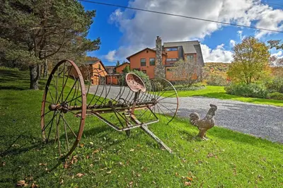 an antique tractor sitting in the grass next to a house at Catskill Ski Mountain Retreat with Private Pool in Big Indian
