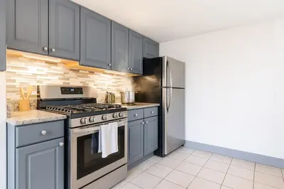 a kitchen with gray cabinets and a stainless steel refrigerator at Convention Center 1BR Condo Downtown Hartford and GYM in Hartford