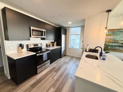 a kitchen with black and white appliances and wooden floors at The Westchester Experience in White Plains