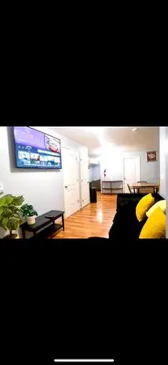 a living room with a couch and a flat screen tv at Lovely Loft in Newark Minutes from NYC, EWR & American Dream Mall in Newark