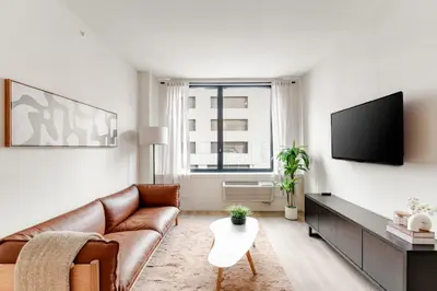a living room with a couch and a flat screen tv at One Grove in Jersey City in Jersey City