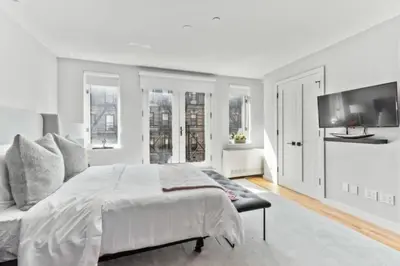 a white bedroom with a large bed and a flat screen tv at Luxe Studio with Charming Juliet Balcony in New York
