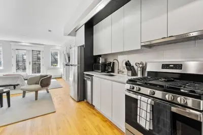a kitchen with white cabinets and a stove top oven at Luxe Studio with Charming Juliet Balcony in New York