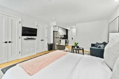 a white bedroom with a large bed and a couch at Luxe Studio with Charming Juliet Balcony in New York