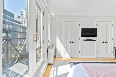 a bedroom with a bed and a large window at Luxe Studio with Charming Juliet Balcony in New York