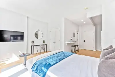 a white bedroom with a bed and a table at Studio w Charming Juliet Balcony in Upper East in New York