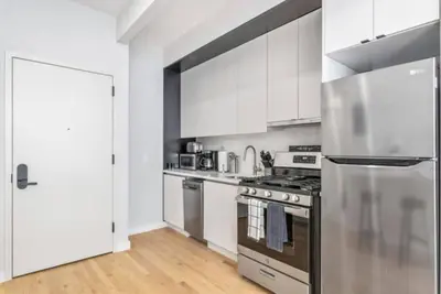 a kitchen with white cabinets and a stainless steel refrigerator at Studio w Charming Juliet Balcony in Upper East in New York