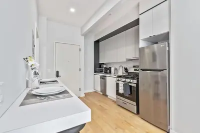 a kitchen with white cabinets and a stainless steel refrigerator at Studio w Charming Juliet Balcony in Upper East in New York