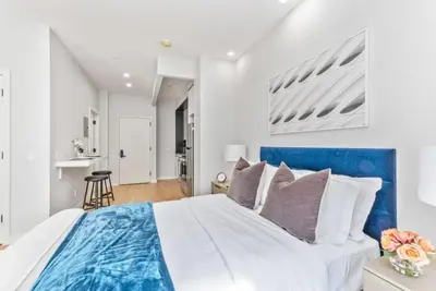 a bedroom with a large bed with a blue headboard at Studio w Charming Juliet Balcony in Upper East in New York