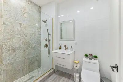 a white bathroom with a shower and a sink at Studio w Charming Juliet Balcony in Upper East in New York