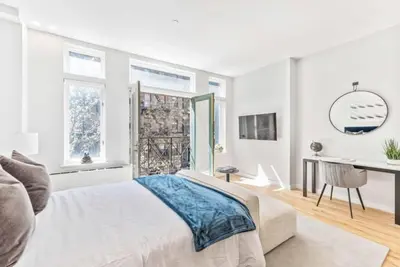 a bedroom with a bed and a desk and windows at Studio w Charming Juliet Balcony in Upper East in New York
