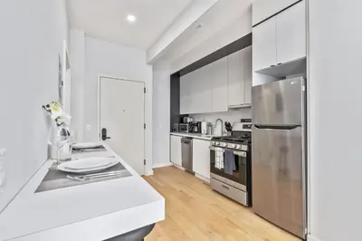 a kitchen with white cabinets and a stainless steel refrigerator at Studio w Charming Juliet Balcony in Upper East in New York