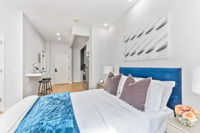 a bedroom with a blue and white bed with pillows at Studio w Charming Juliet Balcony in Upper East in New York