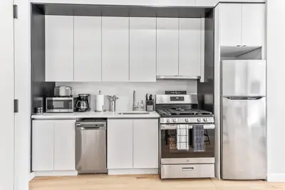 a kitchen with white cabinets and stainless steel appliances at Studio w Charming Juliet Balcony in Upper East in New York