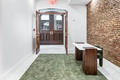 a hallway with a door and a table and a brick wall at Landmarked NYC Townhome - Sleeps 10 -Group-Friendly in New York
