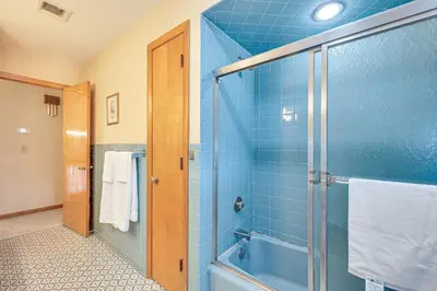 a blue tiled bathroom with a shower with a glass door at Watertown Home with Yard 1 Mi to Echo Lake Park! in Watertown