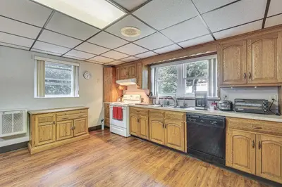 a large kitchen with wooden cabinets and a large window at Watertown Home with Yard 1 Mi to Echo Lake Park! in Watertown