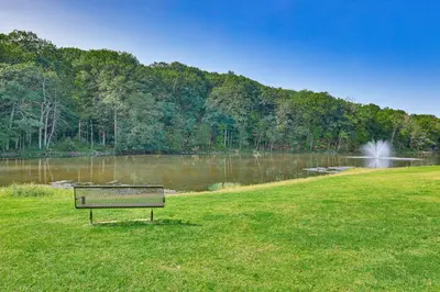 a park bench sitting in the grass next to a lake at Watertown Home with Yard 1 Mi to Echo Lake Park! in Watertown