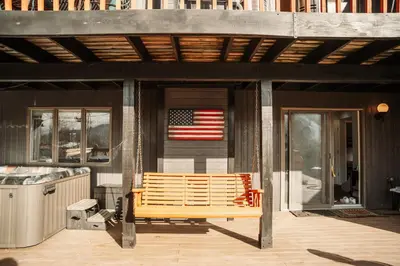 a wooden bench on a porch with an american flag at Hunter Haven - Luxury Cabin Near Mountain Ski Resort in Lanesville