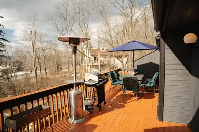 a deck with a grill and chairs and an umbrella at Hunter Haven - Luxury Cabin Near Mountain Ski Resort in Lanesville
