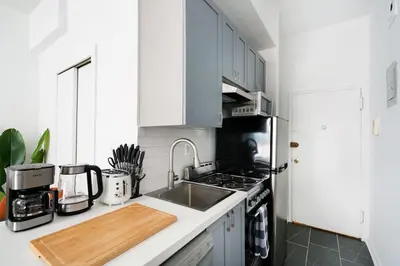 a kitchen with white cabinets and a sink at 74-3C New Studio in Prime UWS - GYM In Building in New York