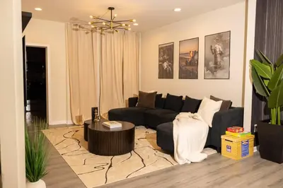 a living room with a black couch and a table at Paloma - Lux Industrial Townhome in Newark