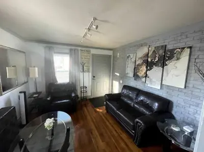 a living room with a black leather couch and a brick wall at New Quaint & Convenient Hideaway Great Location in East Hartford
