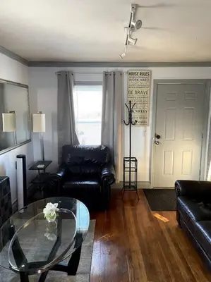 a living room with black leather furniture and a glass table at New Quaint & Convenient Hideaway Great Location in East Hartford