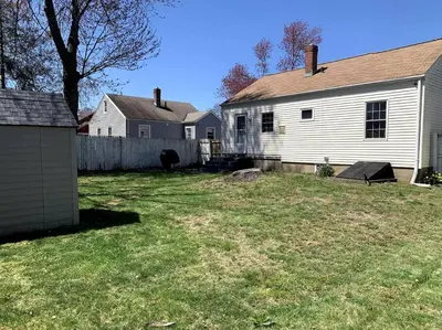 a yard with a white house and a fence at New Quaint & Convenient Hideaway Great Location in East Hartford