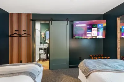 a bedroom with two beds and a tv on the wall at Inn At Mount Snow in West Dover