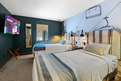 a bedroom with two beds and a tv on the wall at Inn At Mount Snow in West Dover