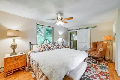 a bedroom with a bed with a ceiling fan and a chair at Home with Private Dock Near Colgate University in Hamilton