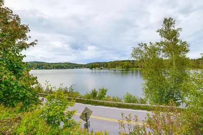 a road next to a lake with a fence at Home with Private Dock Near Colgate University in Hamilton