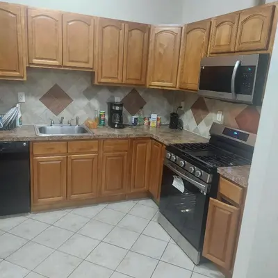 a kitchen with wooden cabinets and a stove and a sink at Deluxe Room E in Jersey City