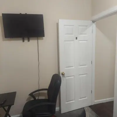 a room with a chair and a tv and a door at Deluxe Room E in Jersey City