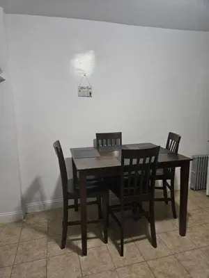 a dining room table with chairs and a light on the wall at Cozy Zone in Williams Bridge