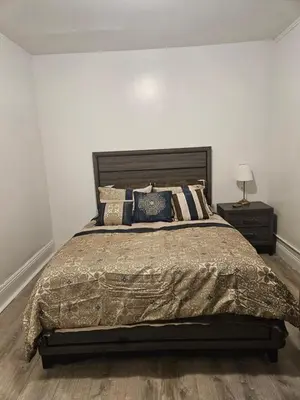 a bedroom with a large bed and a night stand at Cozy Zone in Williams Bridge