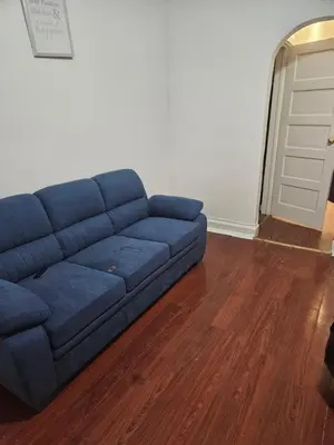 a blue couch in a living room with a wooden floor at Cozy Zone in Williams Bridge