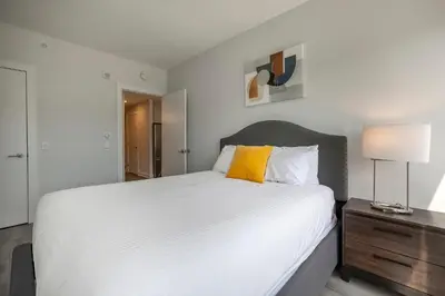 a bedroom with a large white bed with a yellow pillow at Modern Apt Close to Downtown in Stamford