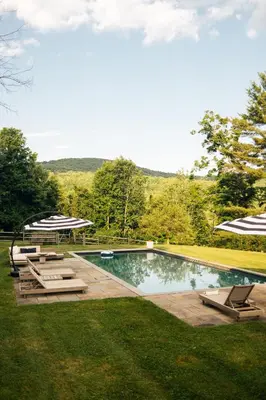 a swimming pool with chairs and umbrellas in a yard at Stylish Rural Sanctuary Perfect for Every Season! in East Chatham