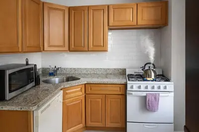 a kitchen with wooden cabinets and a white stove top oven at Hoboken 15 Min Train to Manhattan Full Kitchen in Hoboken