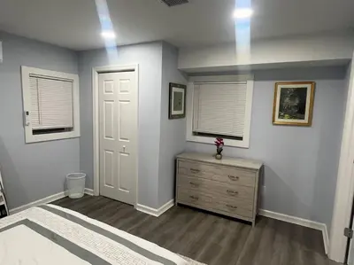 a bedroom with a dresser and two windows and a door at Charming Unit in Yonkers Close to NYC in Yonkers