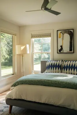 a bedroom with a bed with a ceiling fan and windows at Stunning All-Season Renovated Barn Escape! in East Chatham