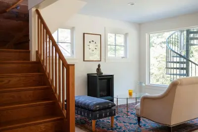 a living room with a staircase and a chair at Stunning All-Season Renovated Barn Escape! in East Chatham