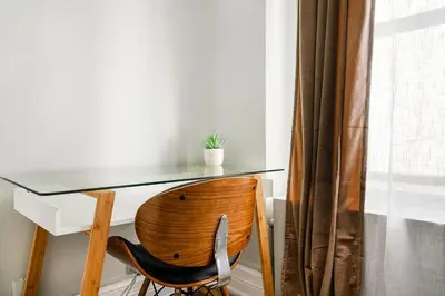a glass desk with a wooden chair next to a window at 73-508 New 1BR 1Bth UWS Doorman Gym in New York