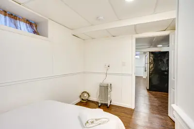 a white room with a bed and a hallway at Shared Yard, 4 Mi to NYC Englewood Apartment! in Englewood