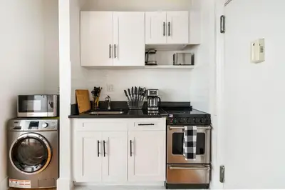 a kitchen with white cabinets and a washer and dryer at 444-1A Beautiful 1BR Midtown West in New York