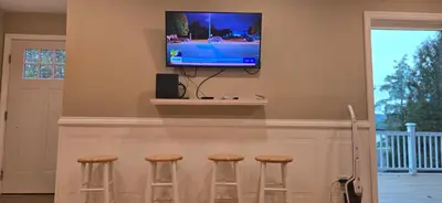 a bar with three stools and a television on a wall at Sparta lakehouse in Sparta